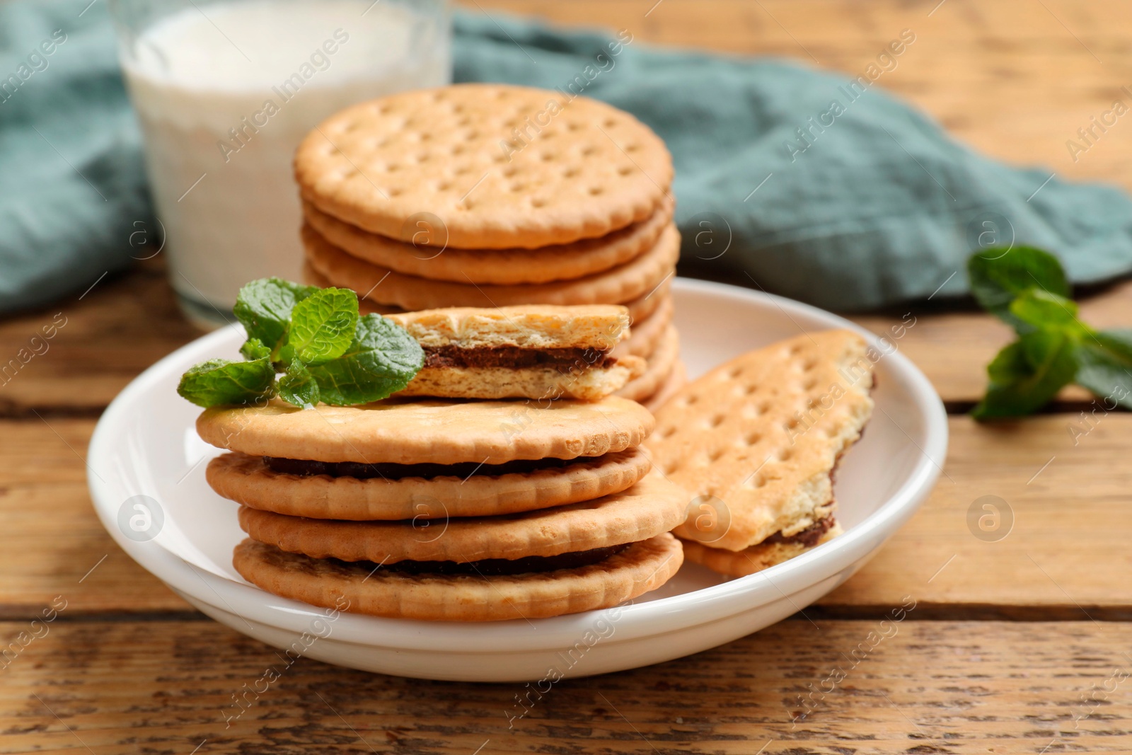 Photo of Tasty sandwich cookies and glass of milk on wooden table, closeup