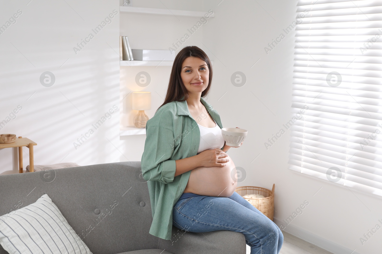 Photo of Beautiful pregnant woman sitting on sofa at home