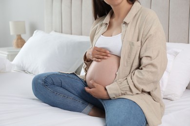 Photo of Pregnant woman on bed at home, closeup