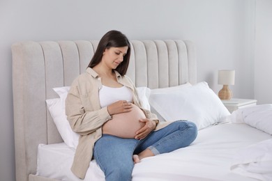 Photo of Beautiful pregnant woman on bed at home