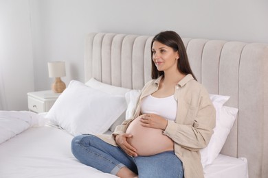 Beautiful pregnant woman on bed at home