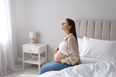 Photo of Beautiful pregnant woman on bed at home