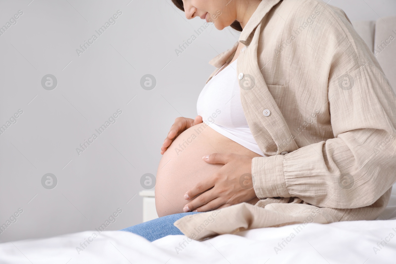 Photo of Pregnant woman on bed at home, closeup. Space for text