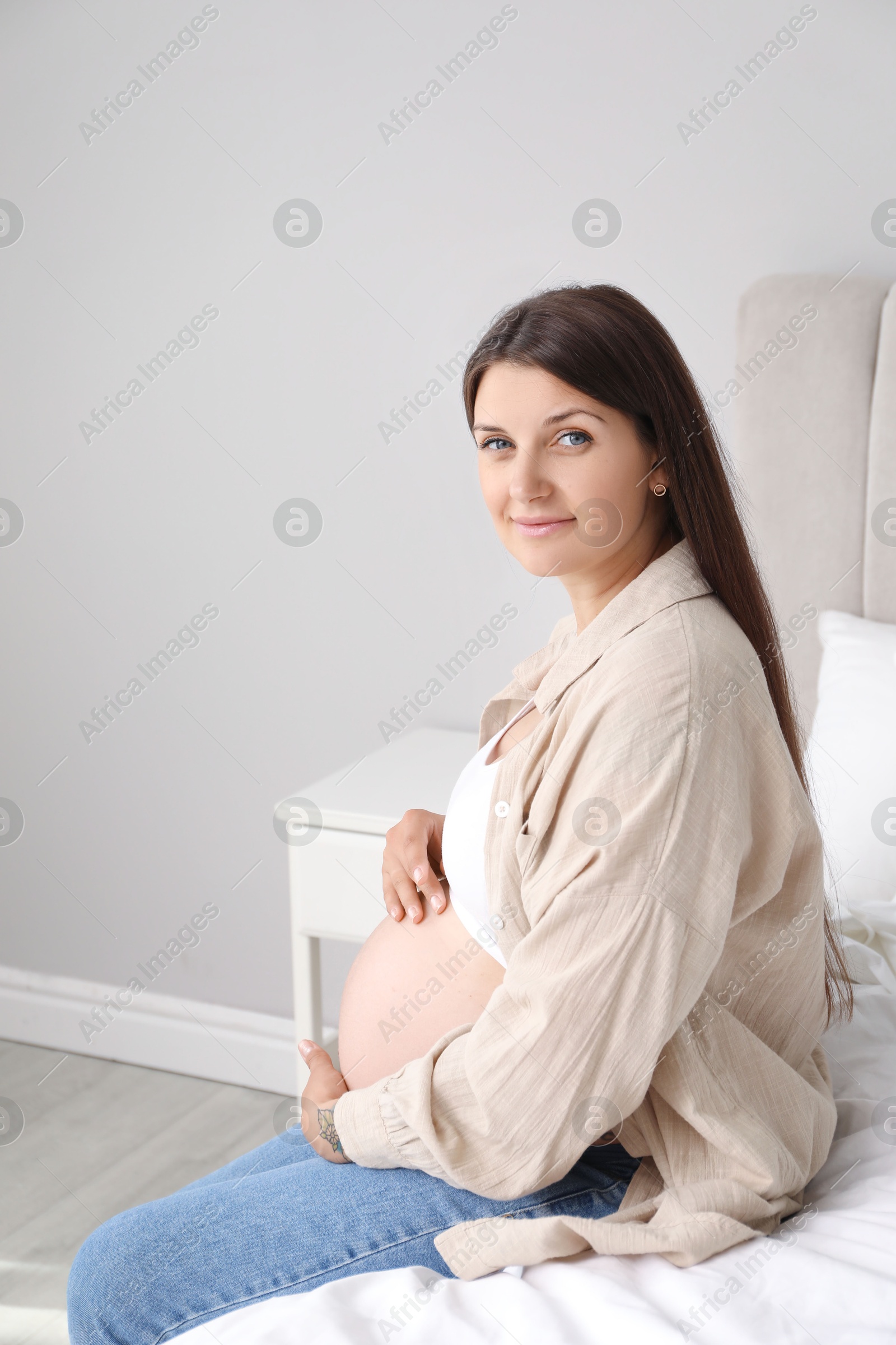 Photo of Beautiful pregnant woman on bed at home