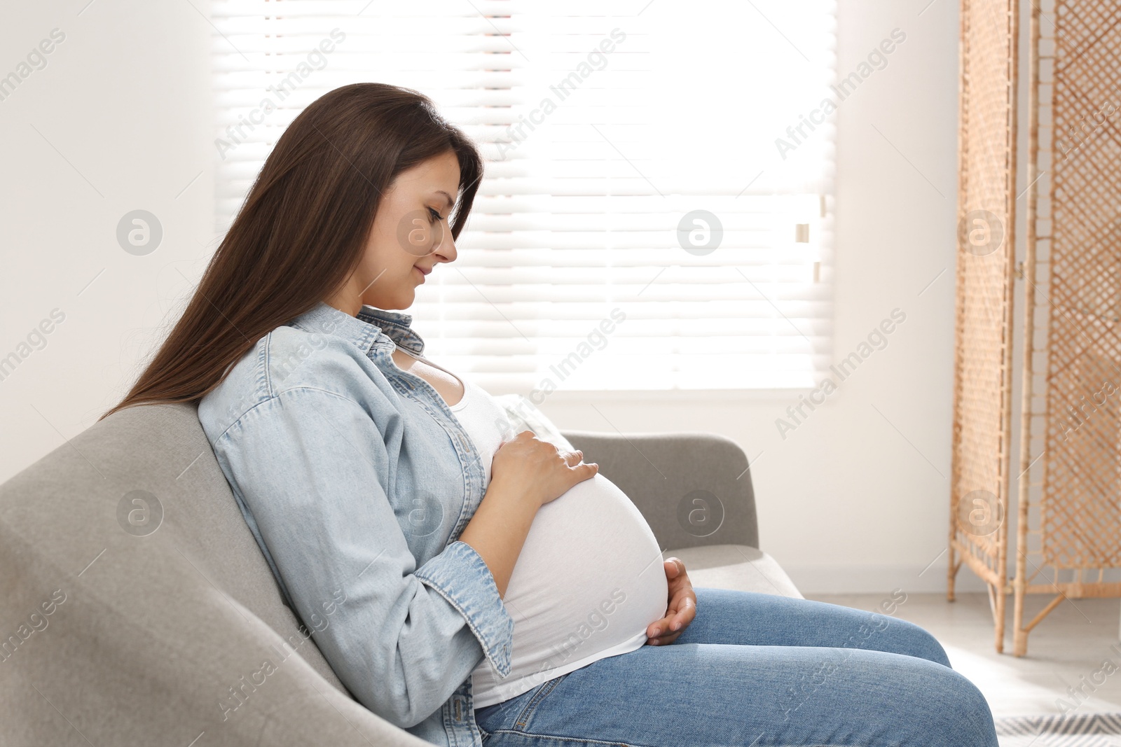 Photo of Beautiful pregnant woman sitting on sofa at home