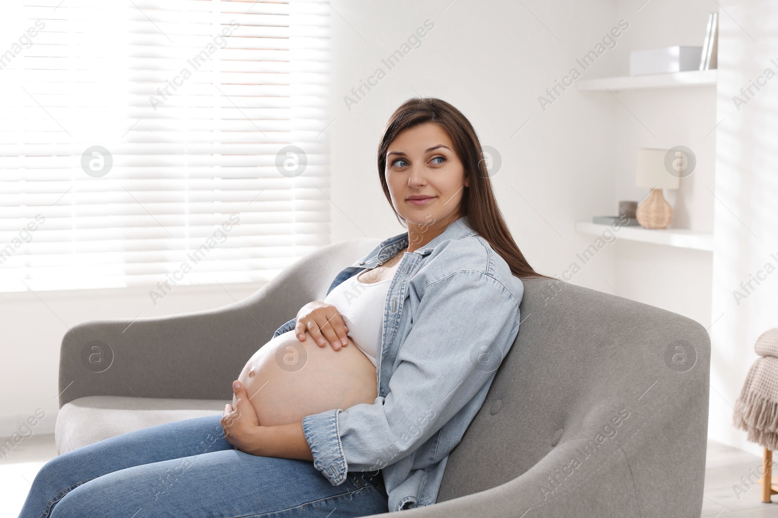 Photo of Beautiful pregnant woman sitting on sofa at home