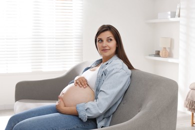 Beautiful pregnant woman sitting on sofa at home