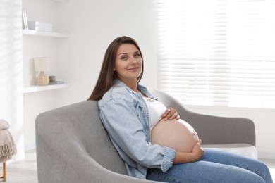 Photo of Beautiful pregnant woman sitting on sofa at home