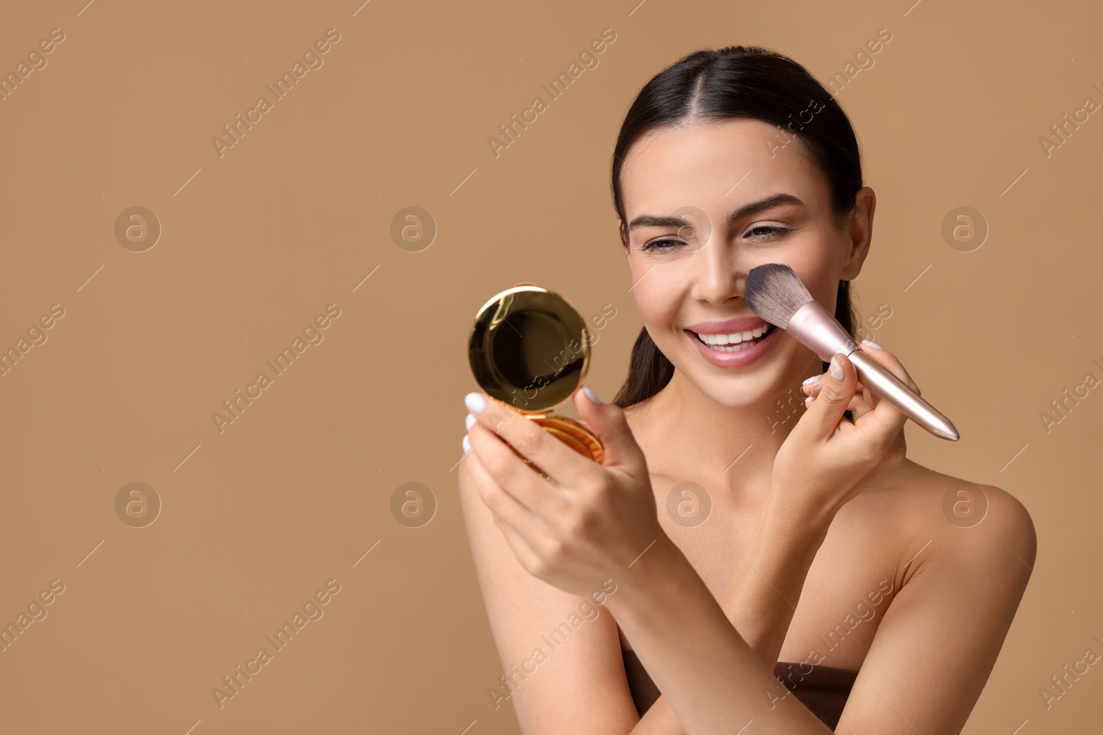 Photo of Smiling woman with cosmetic product applying makeup on beige background. Space for text