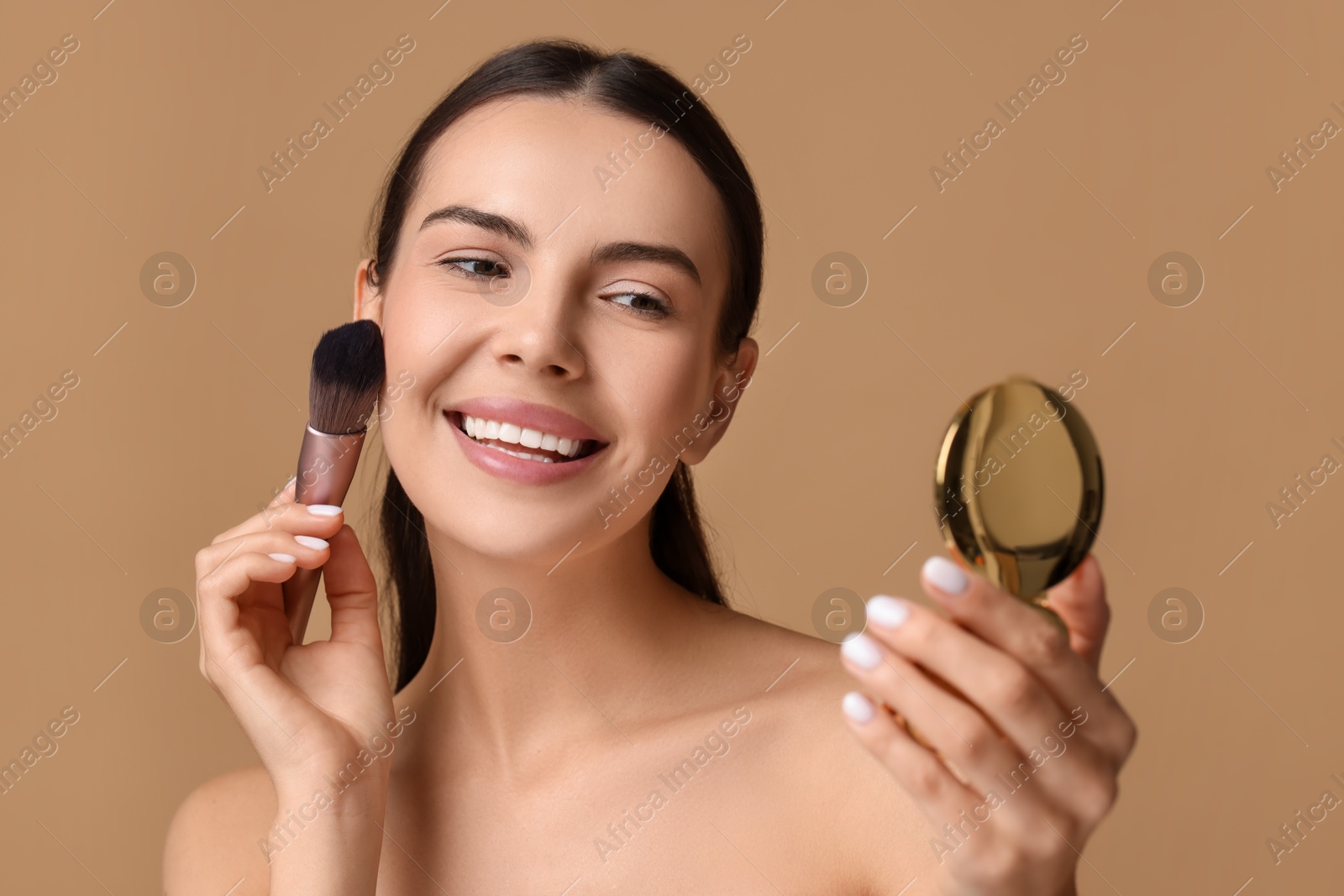 Photo of Smiling woman with cosmetic product applying makeup on beige background