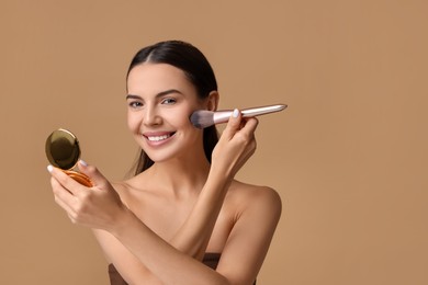 Smiling woman with cosmetic product applying makeup on beige background. Space for text