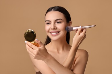 Smiling woman with cosmetic product applying makeup on beige background