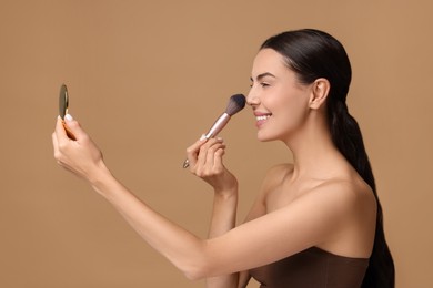 Photo of Smiling woman with cosmetic product applying makeup on beige background