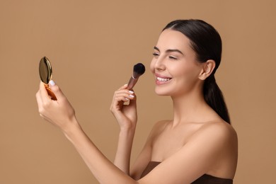 Smiling woman with cosmetic product applying makeup on beige background