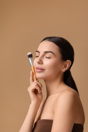 Photo of Beautiful makeup. Attractive woman with brush on beige background