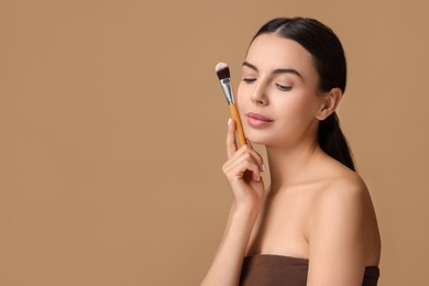 Photo of Beautiful makeup. Attractive woman with brush on beige background, space for text