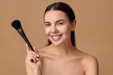 Photo of Beautiful makeup. Smiling woman with brush on beige background