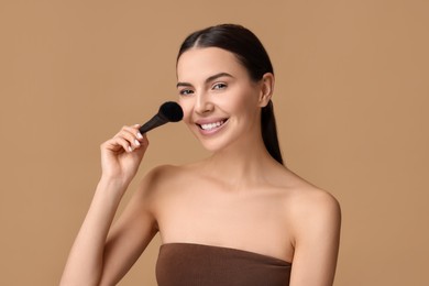 Beautiful makeup. Smiling woman with brush on beige background