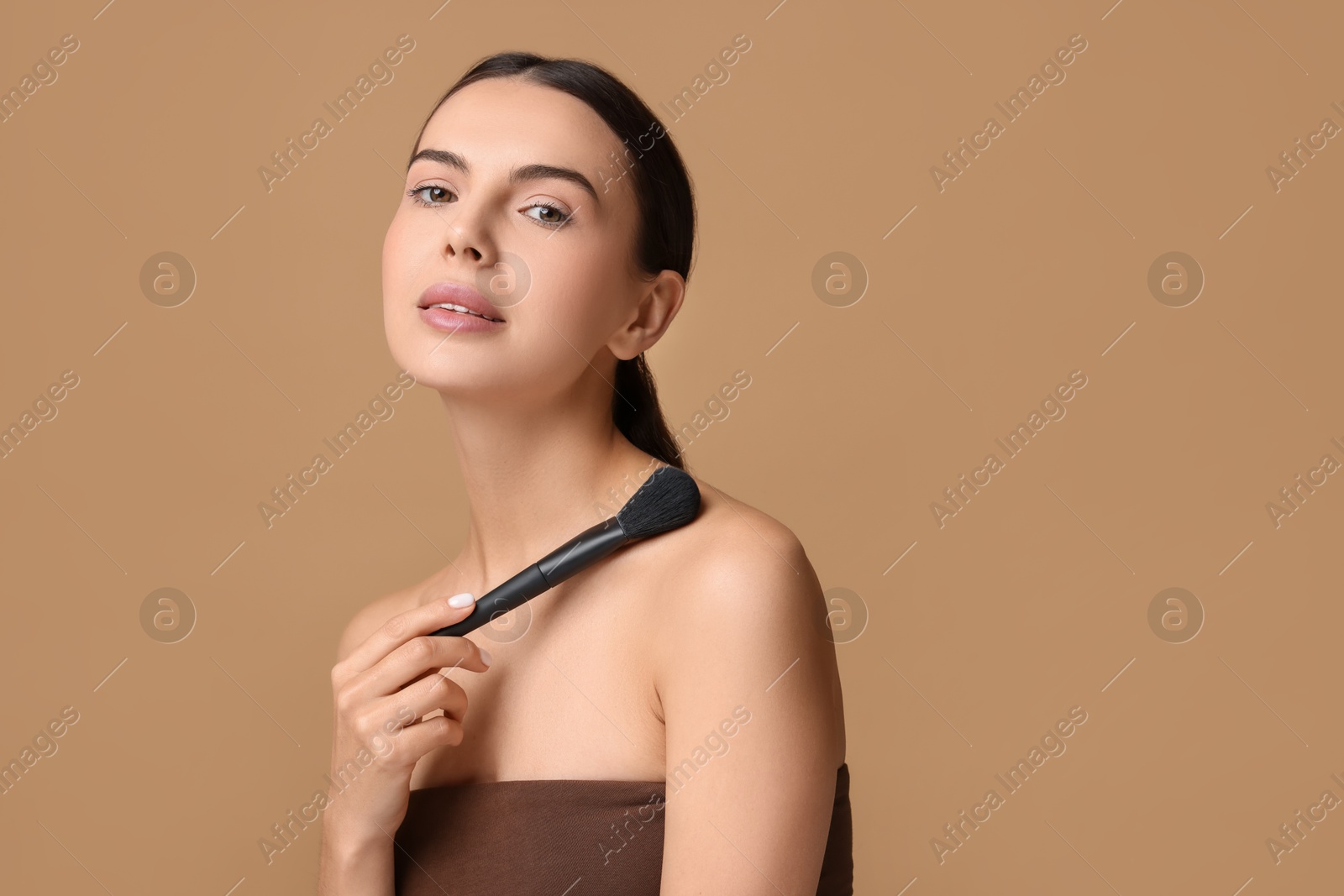 Photo of Beautiful makeup. Attractive woman with brush on beige background, space for text