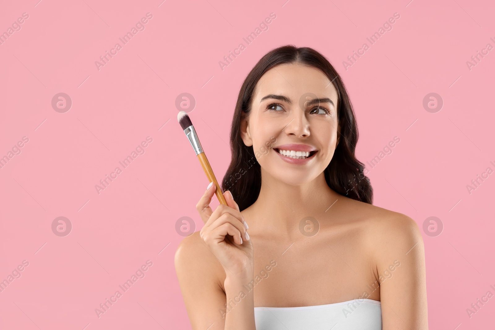 Photo of Beautiful makeup. Smiling woman with brush on pink background, space for text