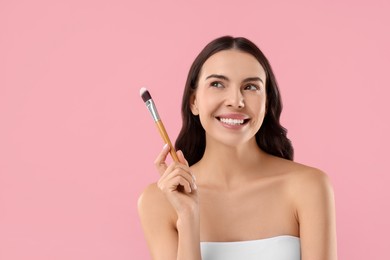 Beautiful makeup. Smiling woman with brush on pink background, space for text