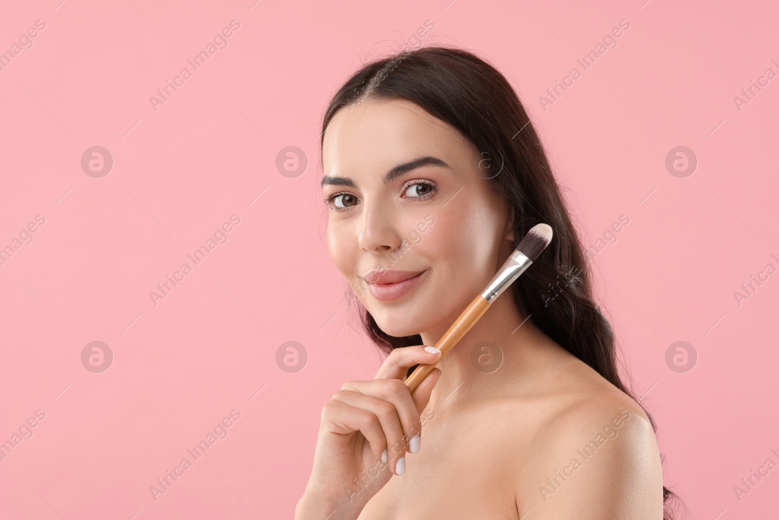 Photo of Beautiful makeup. Attractive woman with brush on pink background, space for text