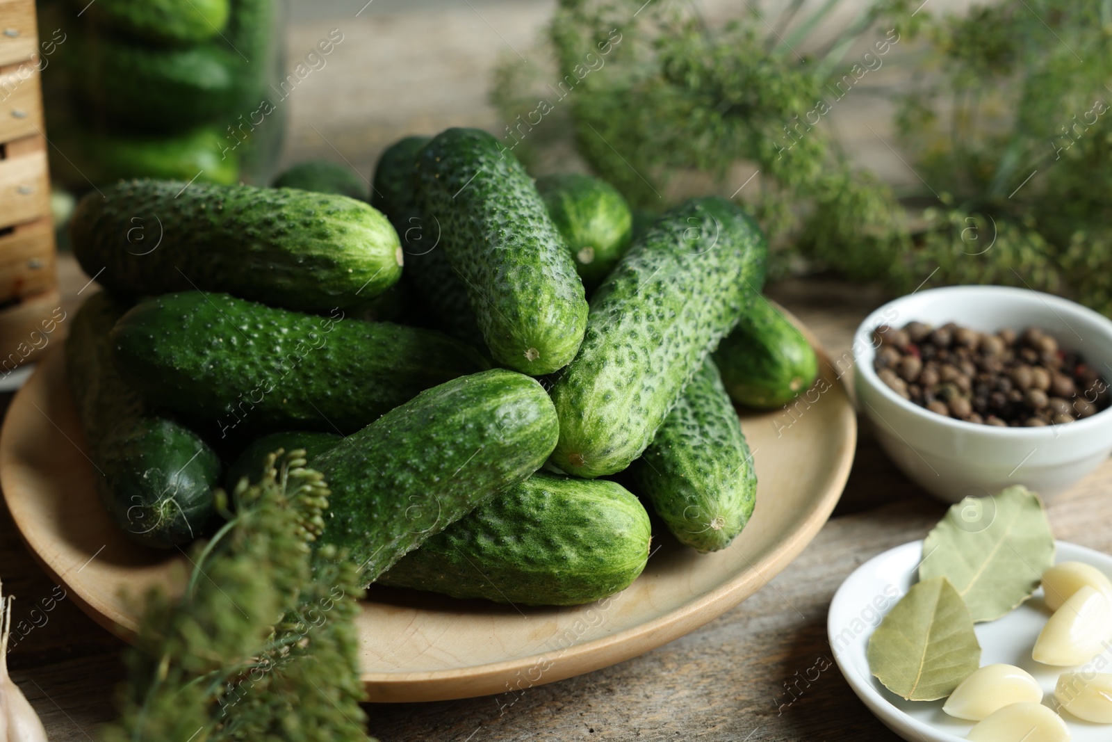 Photo of Fresh cucumbers and spices on wooden table, closeup. Preparation for pickling