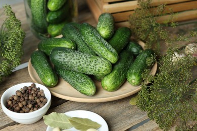 Photo of Fresh cucumbers, dill and spices on wooden table, closeup. Preparation for pickling