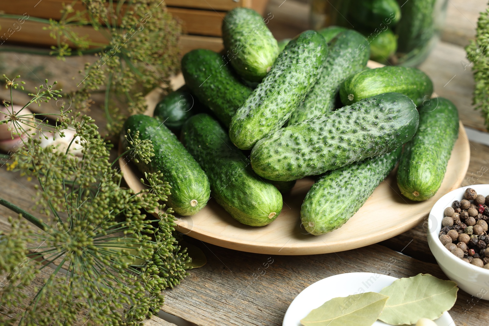 Photo of Fresh cucumbers, dill and spices on wooden table, closeup. Preparation for pickling