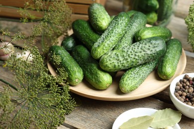 Photo of Fresh cucumbers, dill and spices on wooden table, closeup. Preparation for pickling