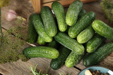 Pile of fresh cucumbers and dill on wooden table, closeup. Preparation for pickling