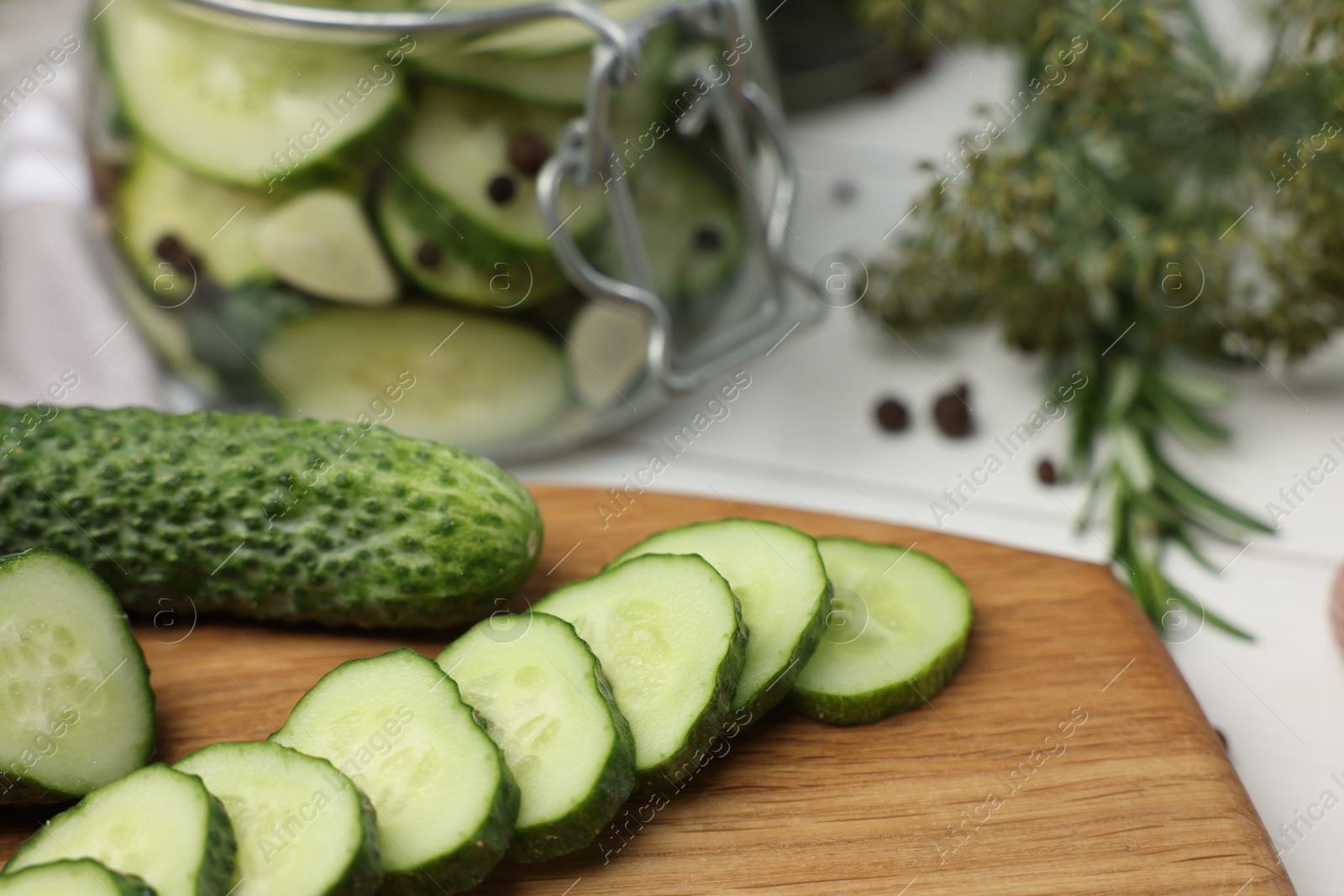 Photo of Board with fresh cut cucumber on light table, closeup. Preparation for pickling