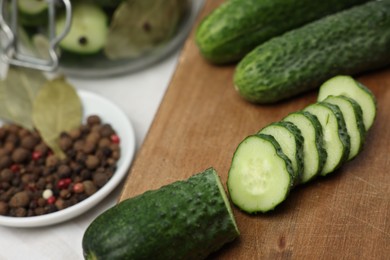 Photo of Board with fresh cut cucumber and spices on table, closeup. Preparation for pickling