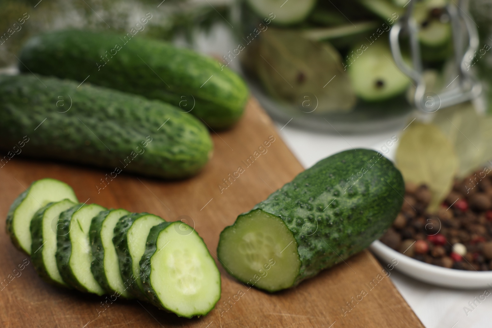 Photo of Board with fresh cut cucumber and spices on table, closeup. Preparation for pickling