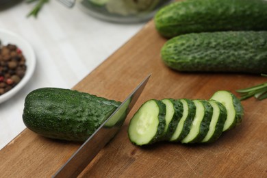 Cutting fresh ripe cucumber at table, closeup