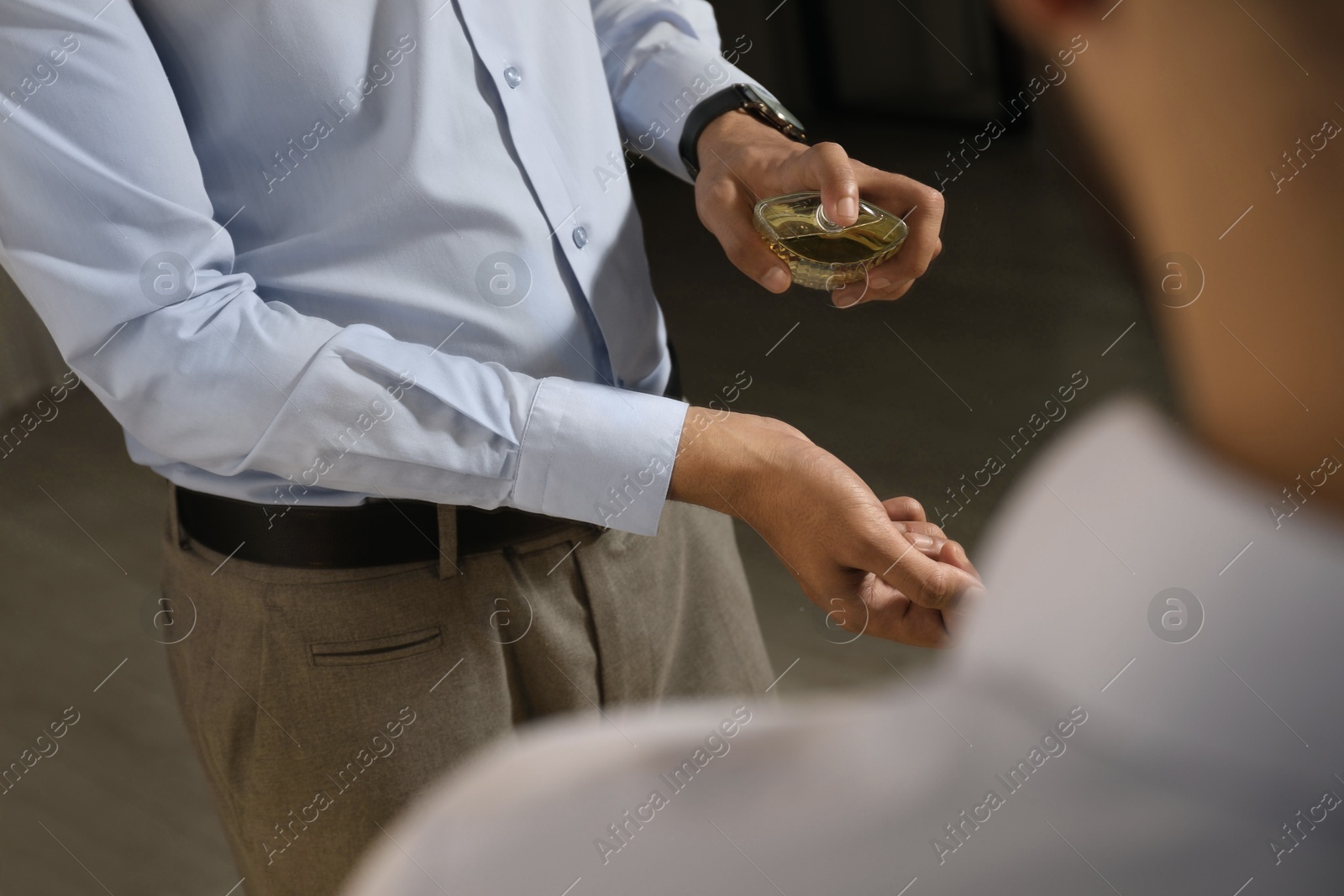 Photo of Man spraying luxury perfume near mirror indoors, closeup