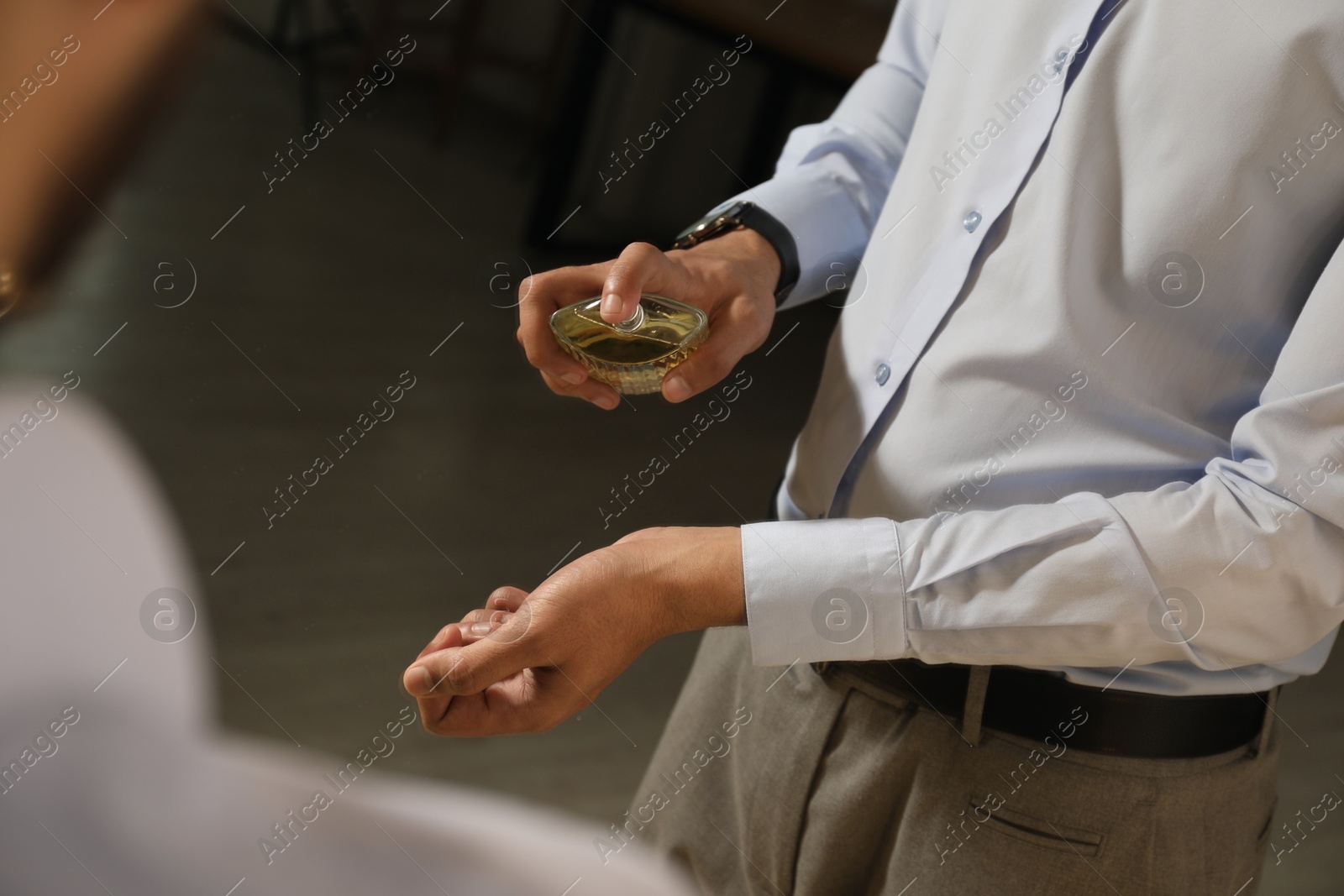 Photo of Man spraying luxury perfume near mirror indoors, closeup