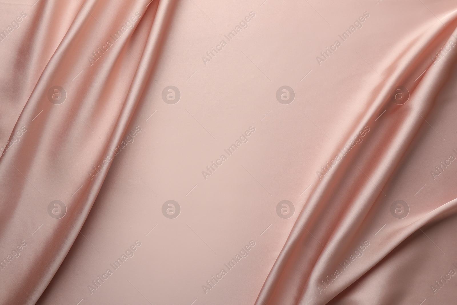 Photo of Crumpled pink silk fabric as background, top view. Space for text