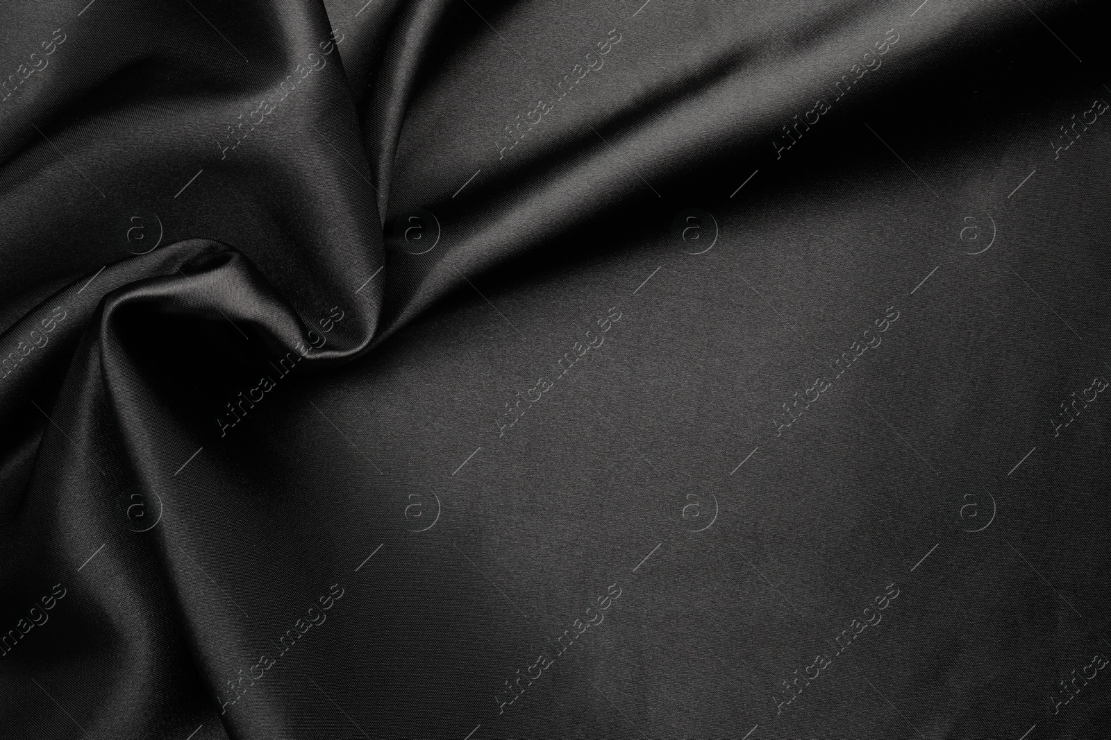 Photo of Crumpled black silk fabric as background, top view. Space for text