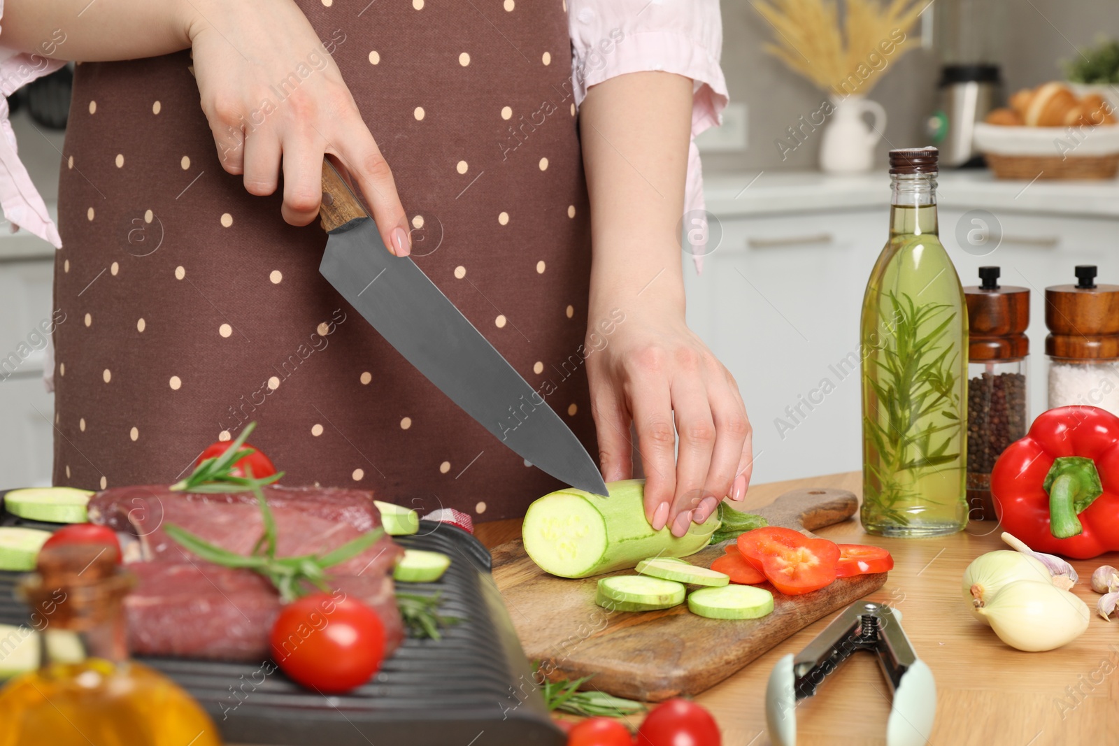 Photo of Woman cooking different products with electric grill at wooden table in kitchen, closeup