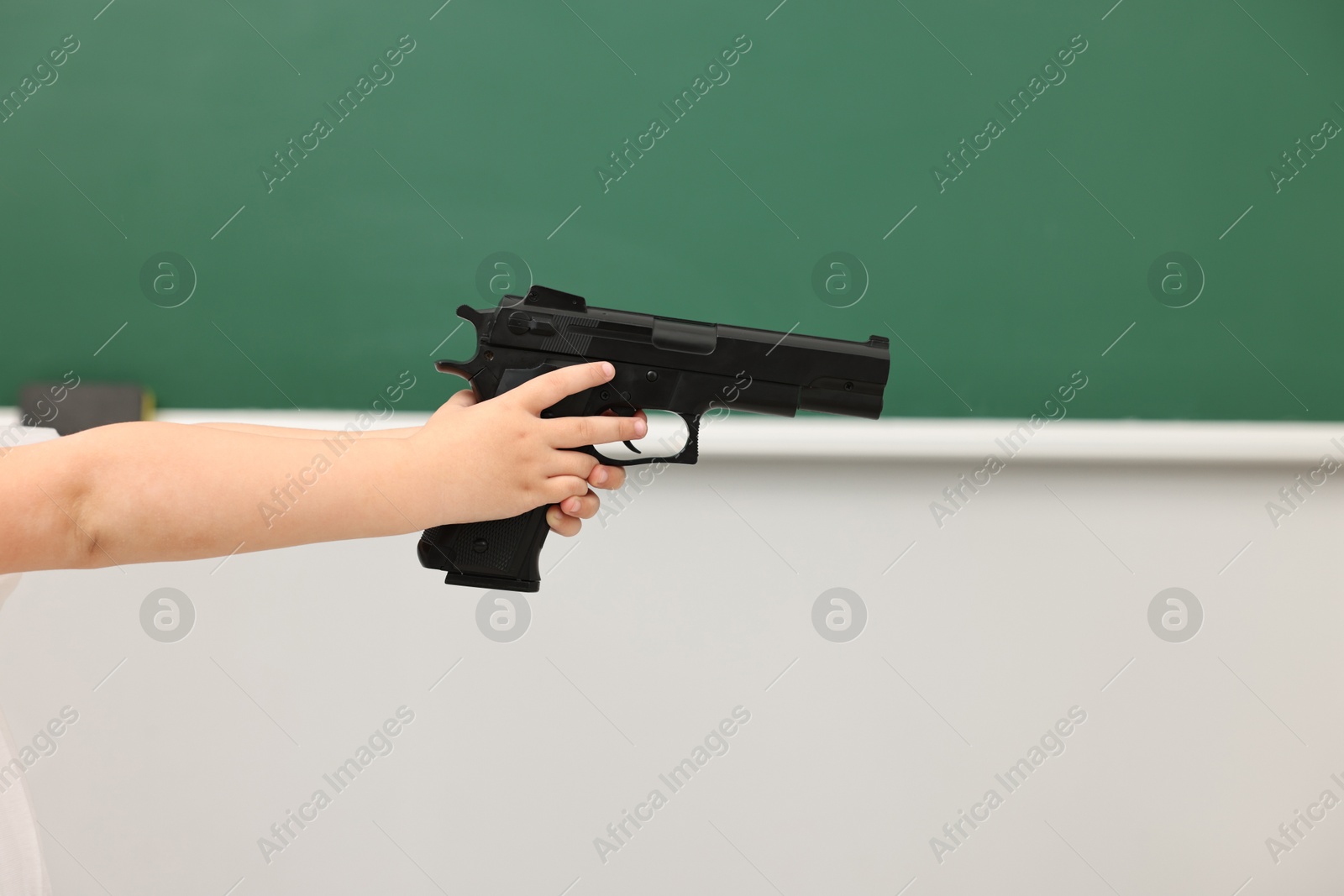 Photo of Child with gun in classroom, closeup. School shooting