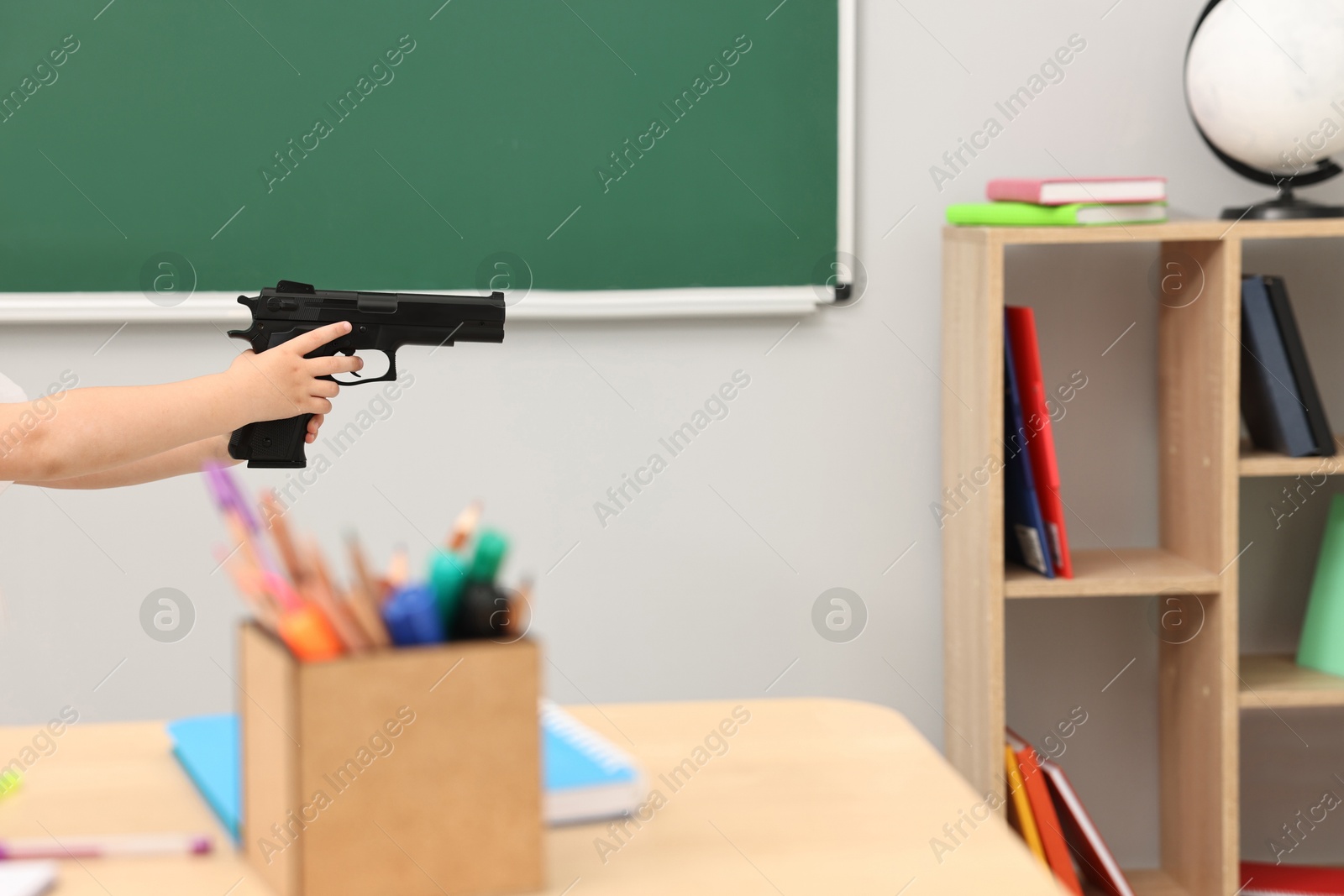 Photo of Child with gun in classroom, closeup. School shooting