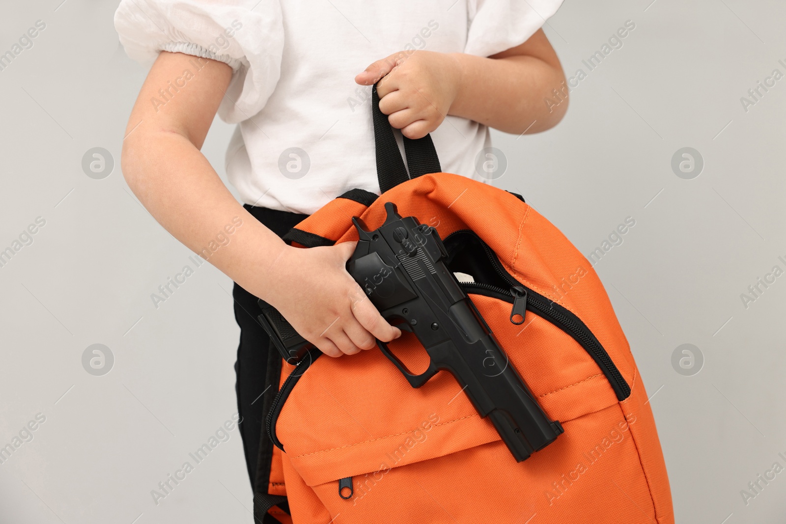 Photo of Child with gun and backpack in classroom, closeup. School shooting