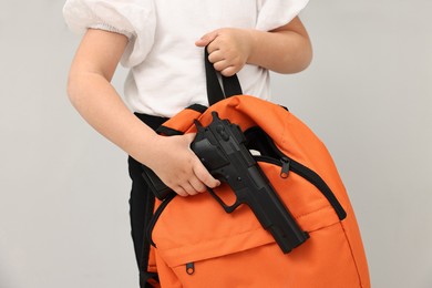 Child with gun and backpack in classroom, closeup. School shooting