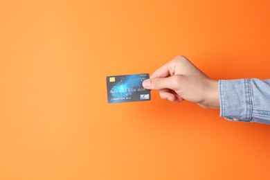 Man holding credit card on orange background, closeup