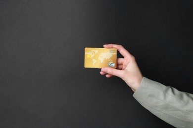 Woman holding credit card on black background, closeup