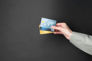 Photo of Woman holding credit cards on black background, closeup