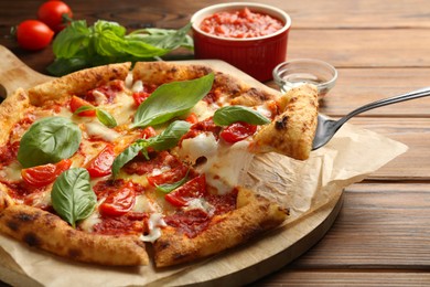 Taking piece of delicious Margherita pizza at wooden table, closeup