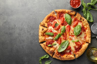 Delicious Margherita pizza, ingredients and cutter on grey table, top view. Space for text