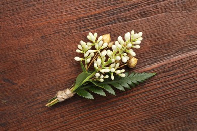 Photo of Small stylish boutonniere on wooden table, top view